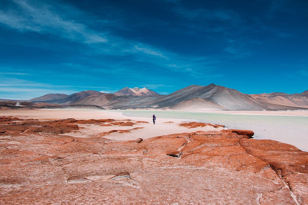 orange desert earth with clear blue skies and man in distance