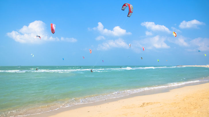 blue water, white sand beach and kite surfers