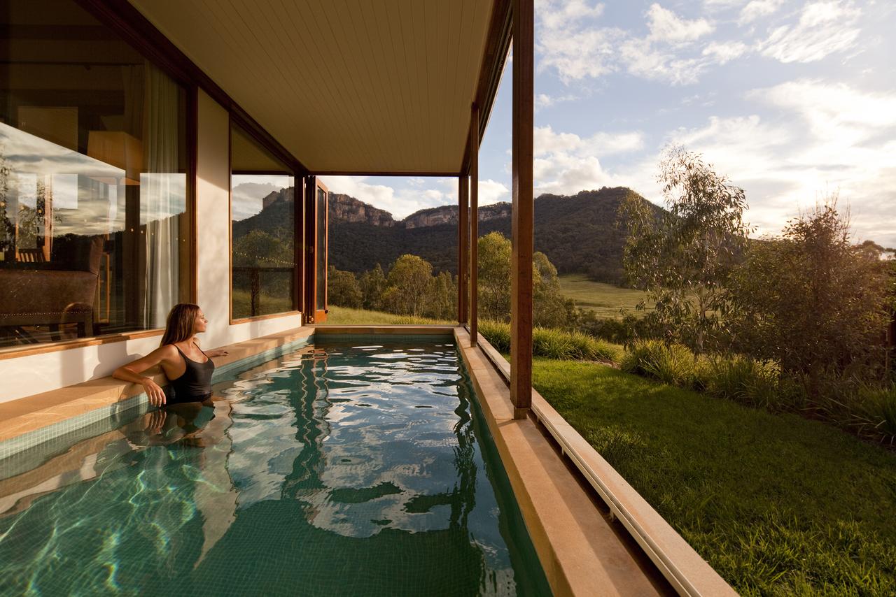 woman gazing over green hills from plunge pool off room