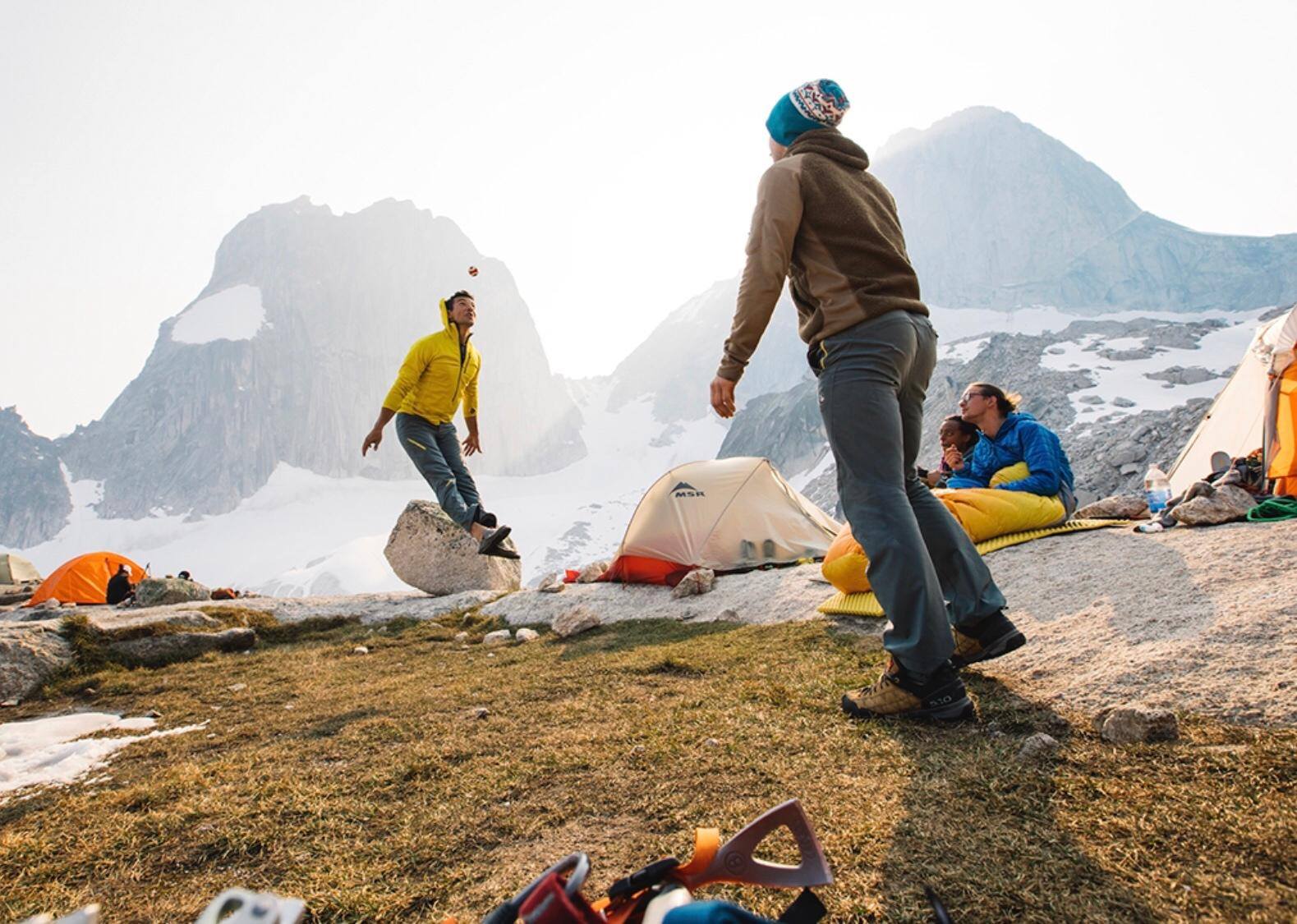 men playing hackey sack, top of mountain with tents