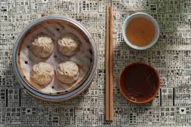 four buns on plate, chopsticks and dipping sauce