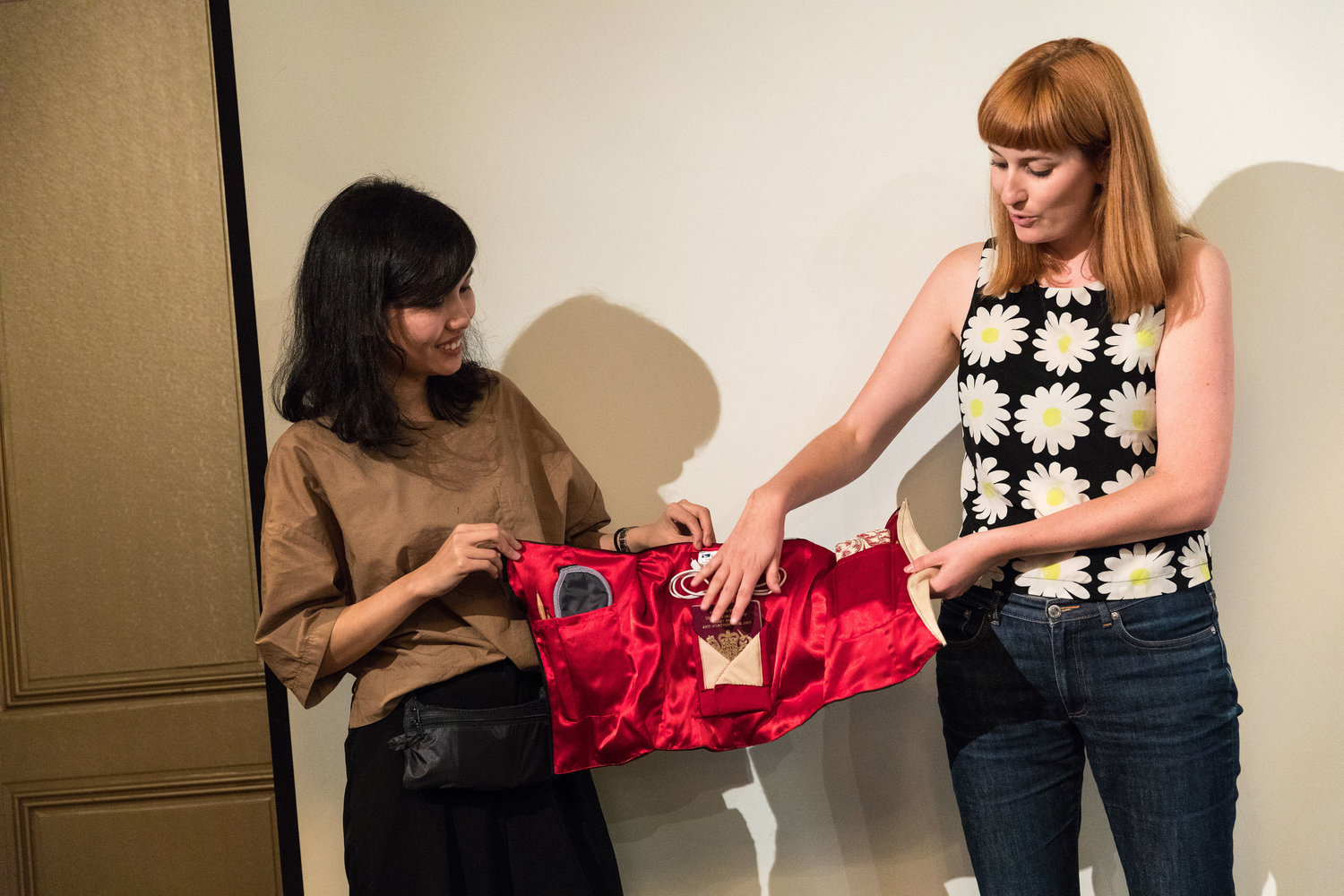 Asian and Caucasian woman presenting red satin bag