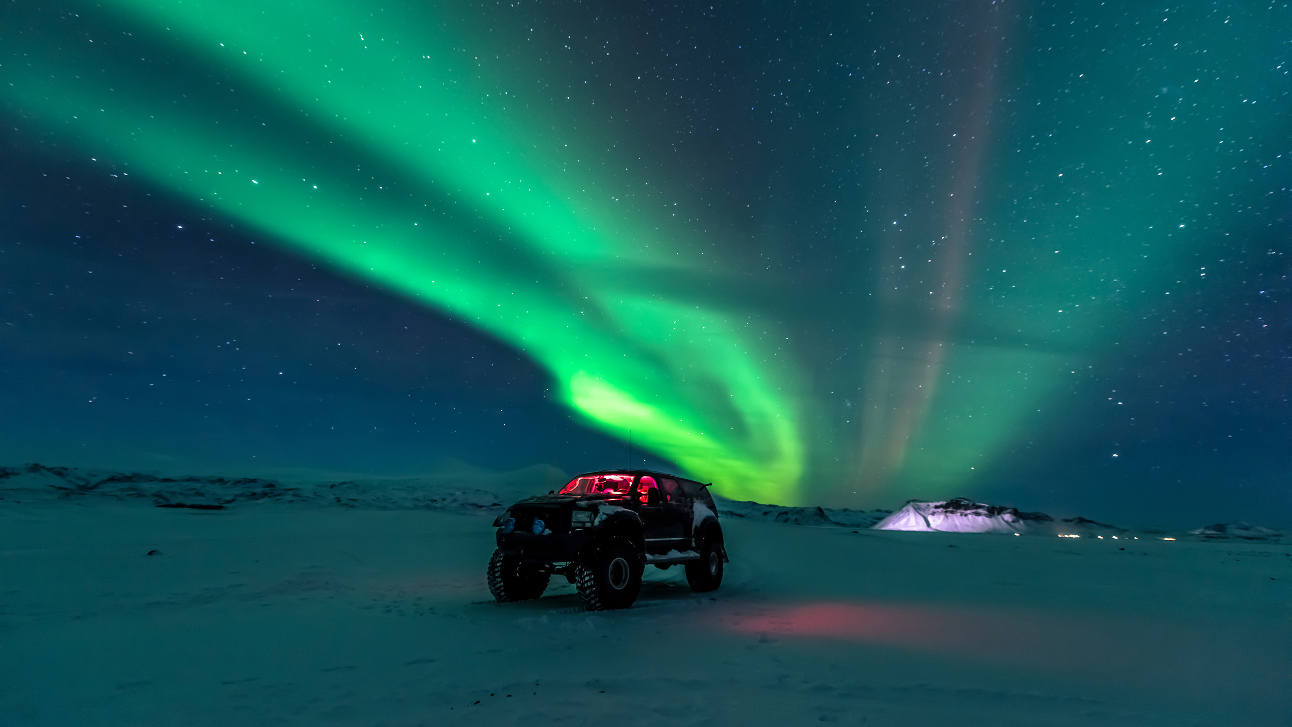 red jeep at night with Aurora Borealis in sky