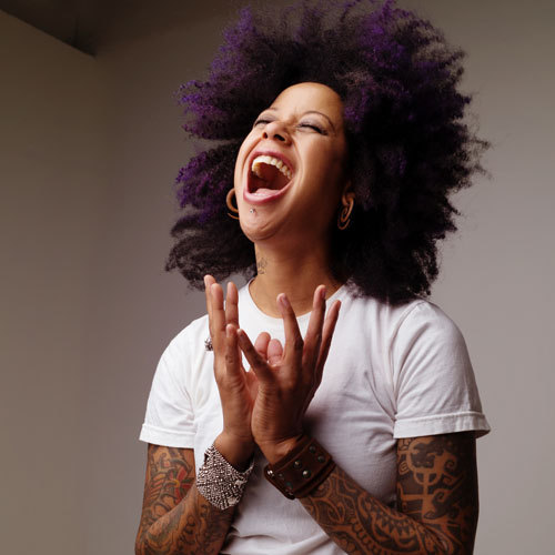 African American woman with purple-tipped afro, head thrown back in laughter