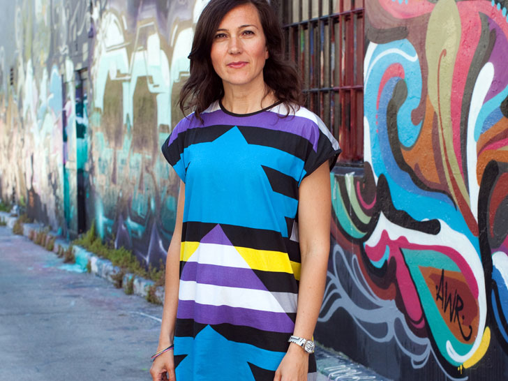 Woman in bright blue and striped dress against graffiti wall