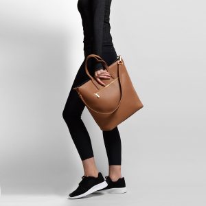 woman in all black carrying russet coloured bag