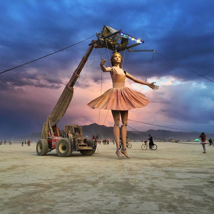 crane lifting large art installation of ballerina in Nevada desert, at sunset