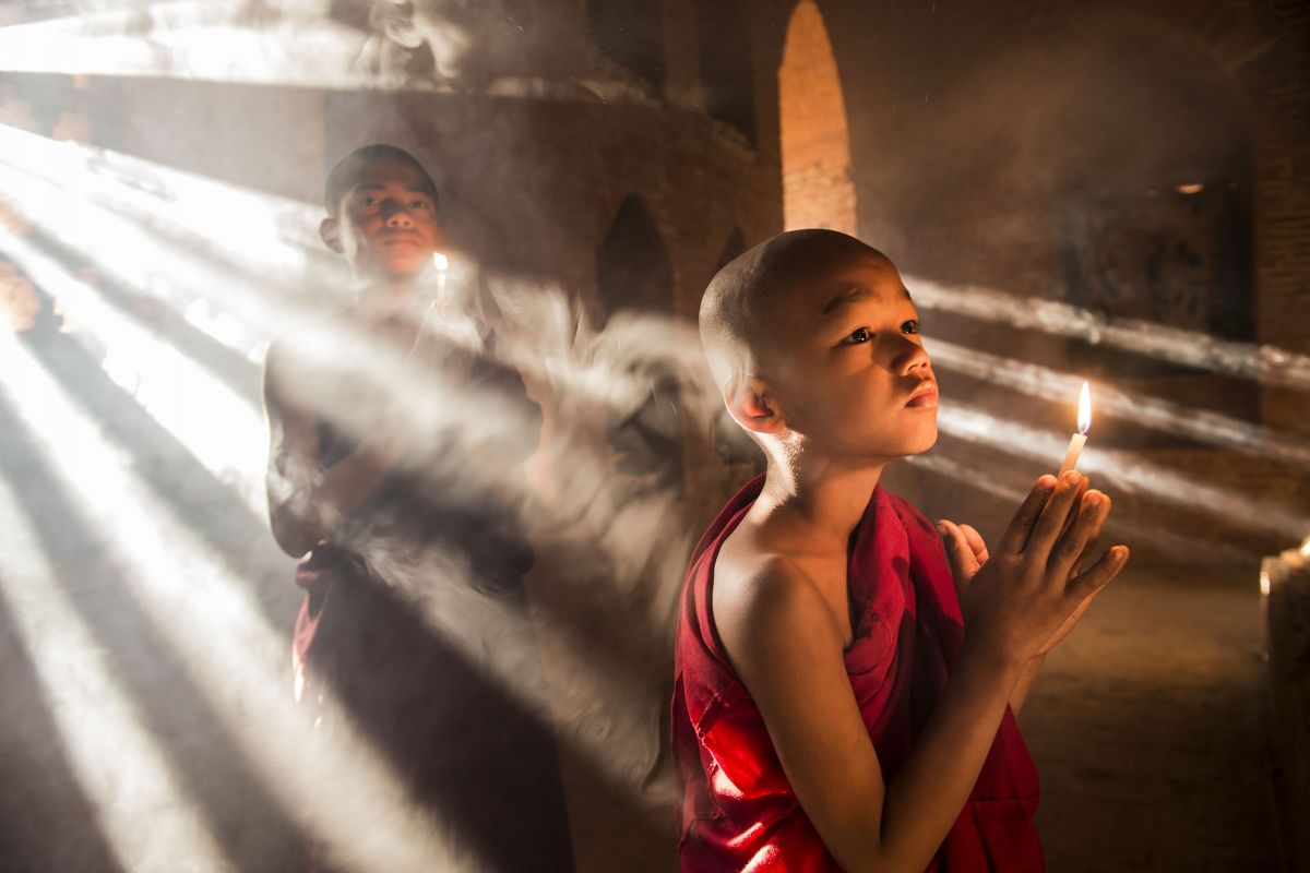 Cambodian monks in red cloth, sunlight streaming behind them