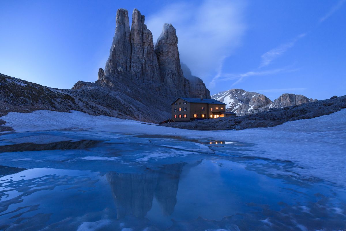 blue night sky with Dolomite Mountains and secluded cabin
