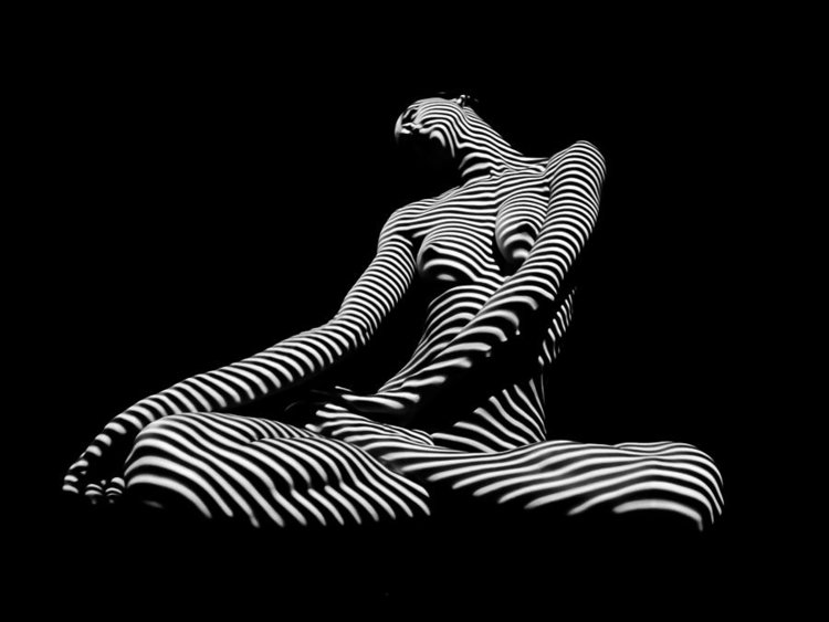 naked woman in shadows playing stripes on her skin