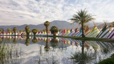 colourful teepees next to a calm lake with palm trees