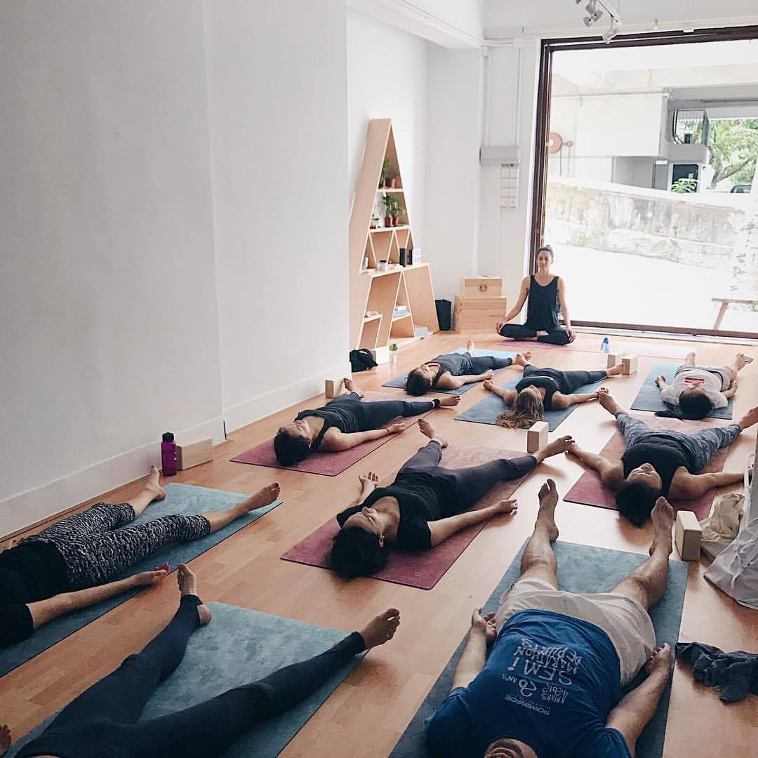 yoga class, students lying on yoga mats with teacher in lotus position