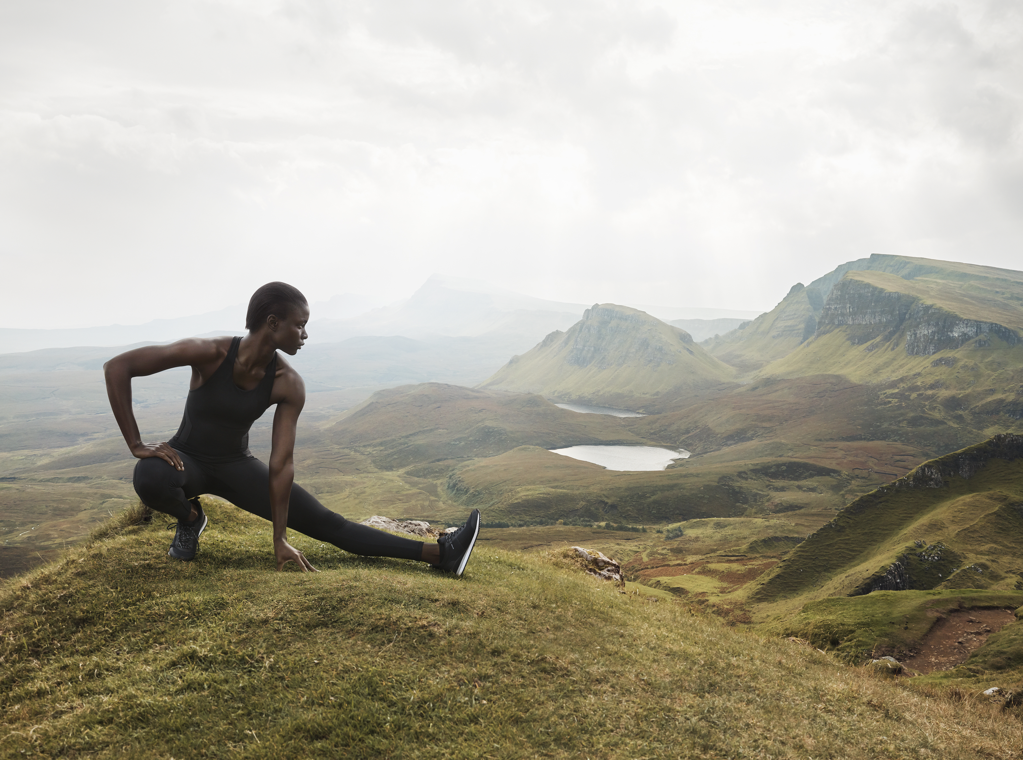 Dark-skinned woman stretching on mountain top