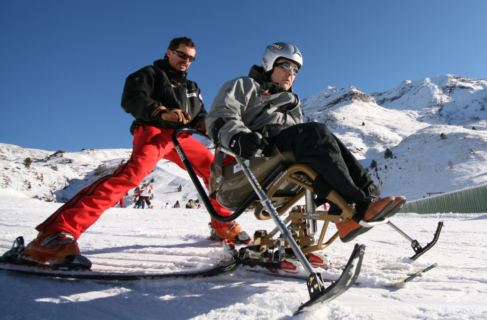 man pushing disable man on special skis on snow