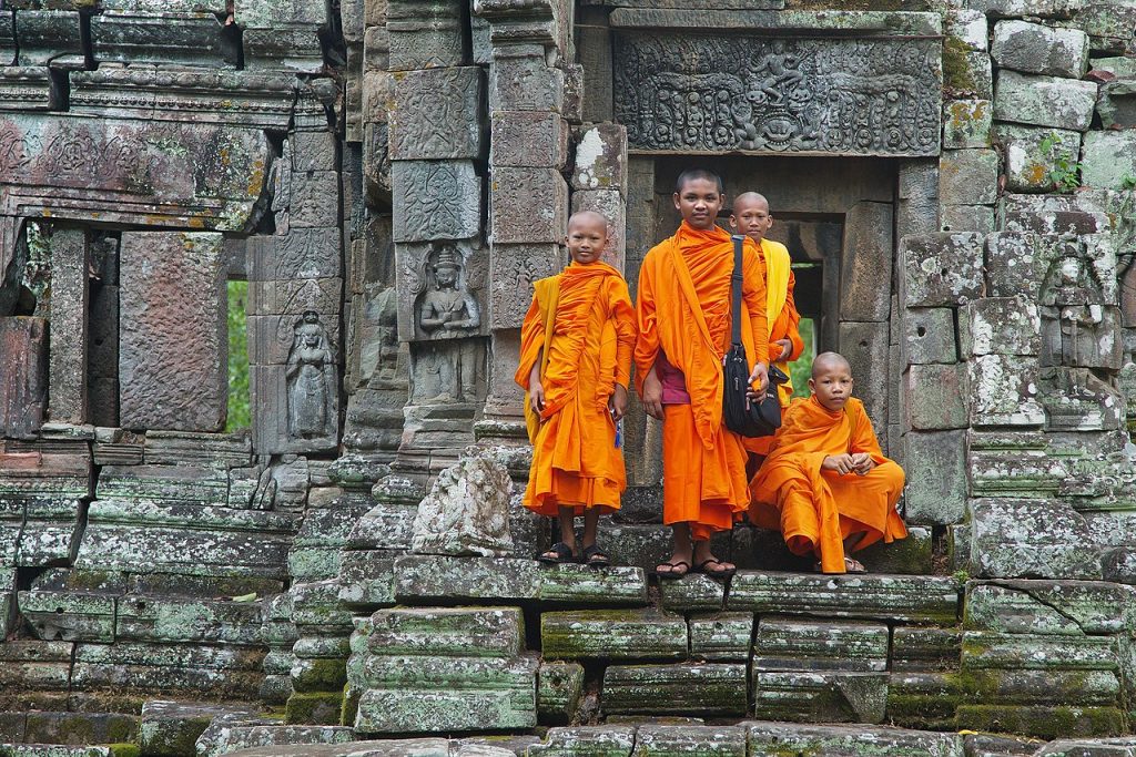 orange-robed young monks standing on temple steps