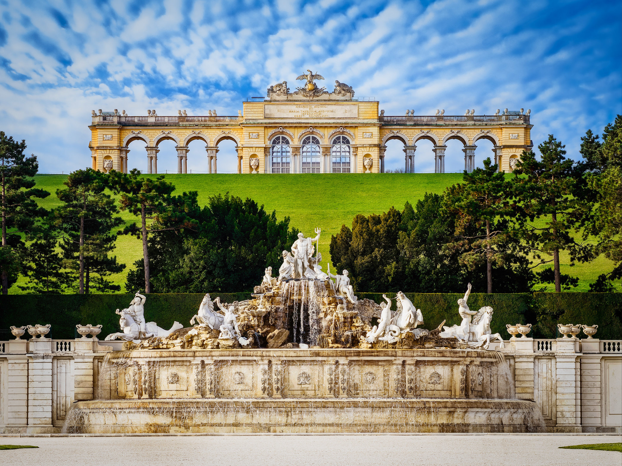 palace on grassy hill, fountain in foreground
