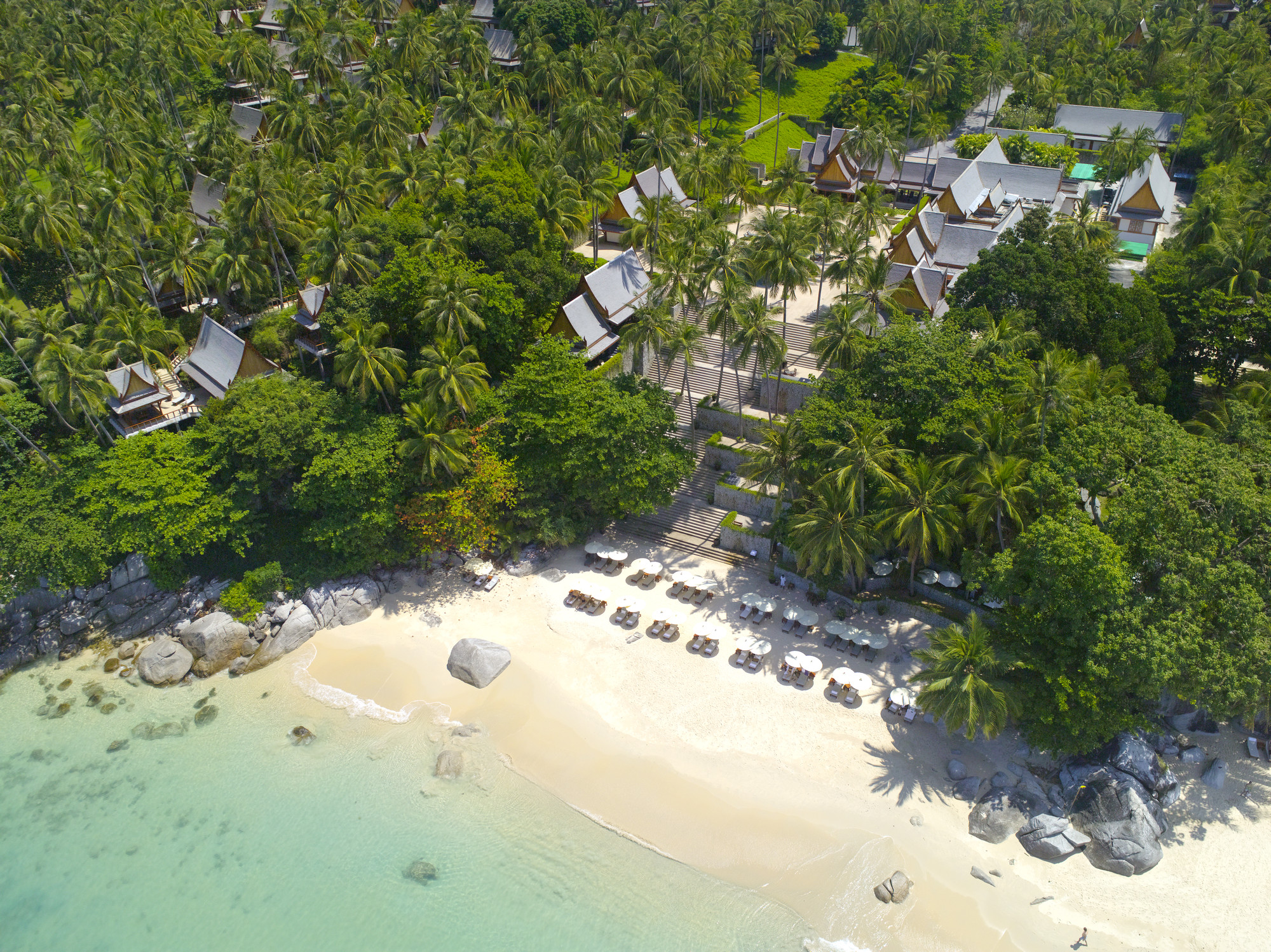 aerial view of white sand beach, turquoise water and beachfront hotel pavilions