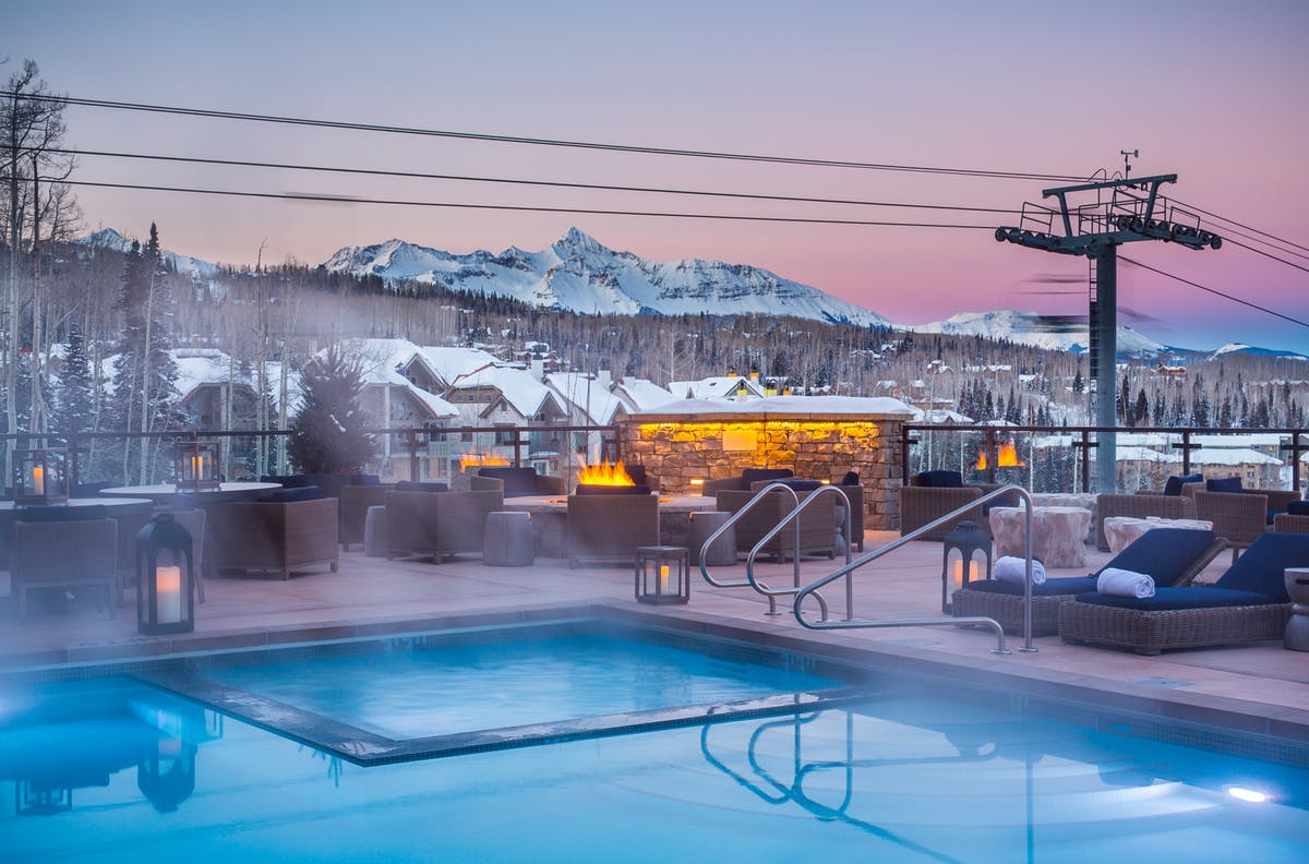 outdoor swimming pool at dusk, snowy mountains
